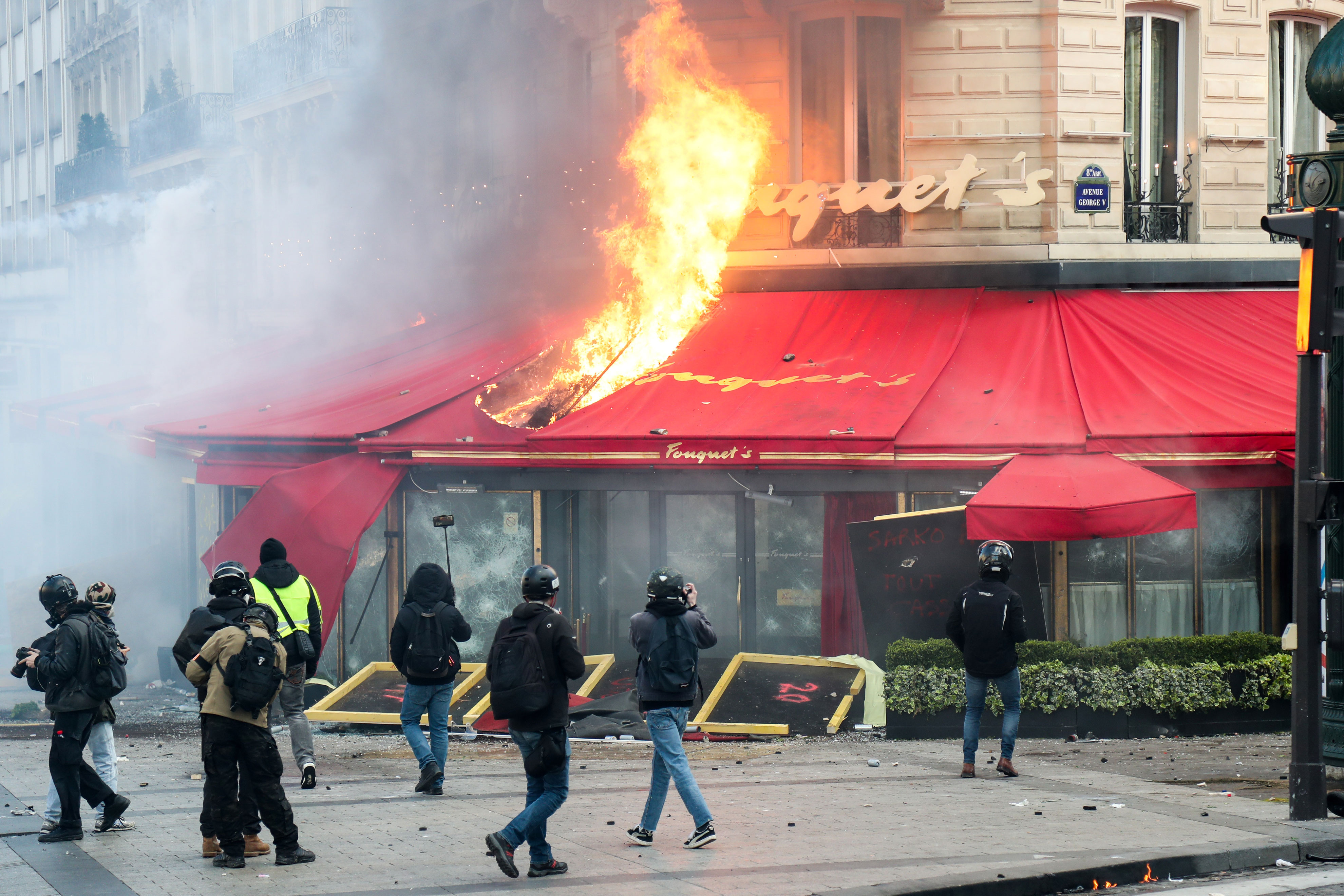 Des manifestants et des « gilets jaunes » devant le restaurant Le Fouquet's en feu, le 16 mars 2019
