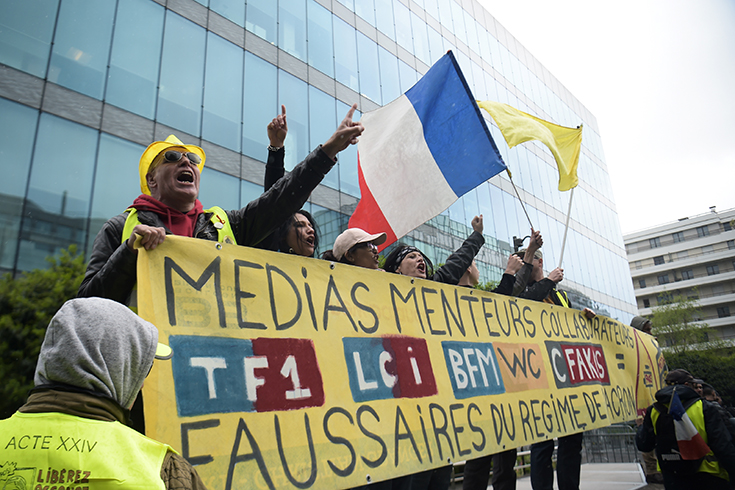 Photographie de manifestants au « gilet jaune » portant une pancarte « Médias menteurs », le 27 avril à Paris.