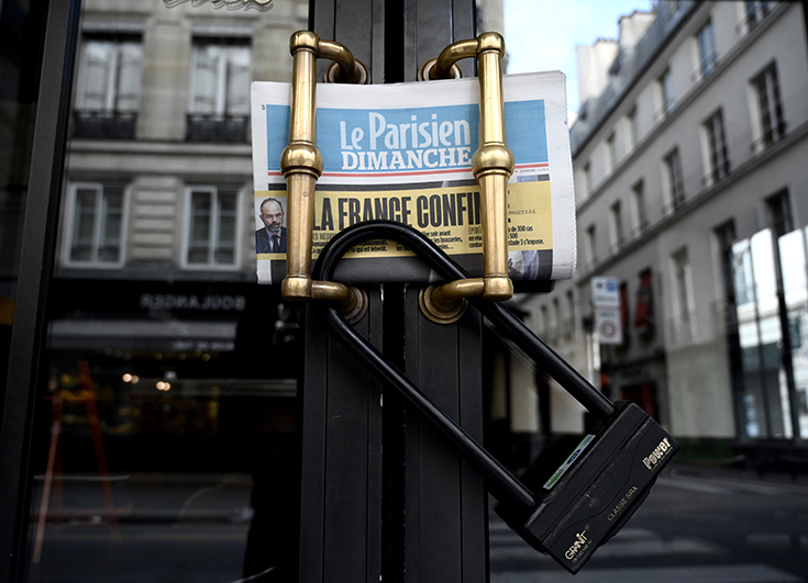 Le journal Le Parisien photographié derrière un cadenas pour illustrer le confinement en France suite à l'épidémie de coronavirus