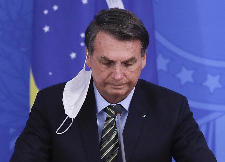 Le président brésilien Jair Bolsonaro lors d'une conférence de presse le 18 mars 2020 pendant l'épidémie de Covid-19. Il porte un masque attaché à une seule oreille et qui pend sur le côté.