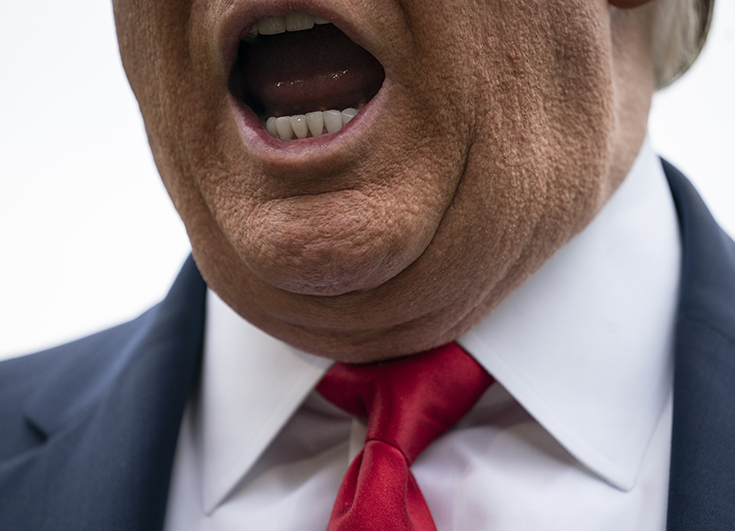 Photographie de la bouche du président des Etats-Unis Donald Trump. On voit le col de sa chemise blanche avec une cravate rouge et un costume bleu.