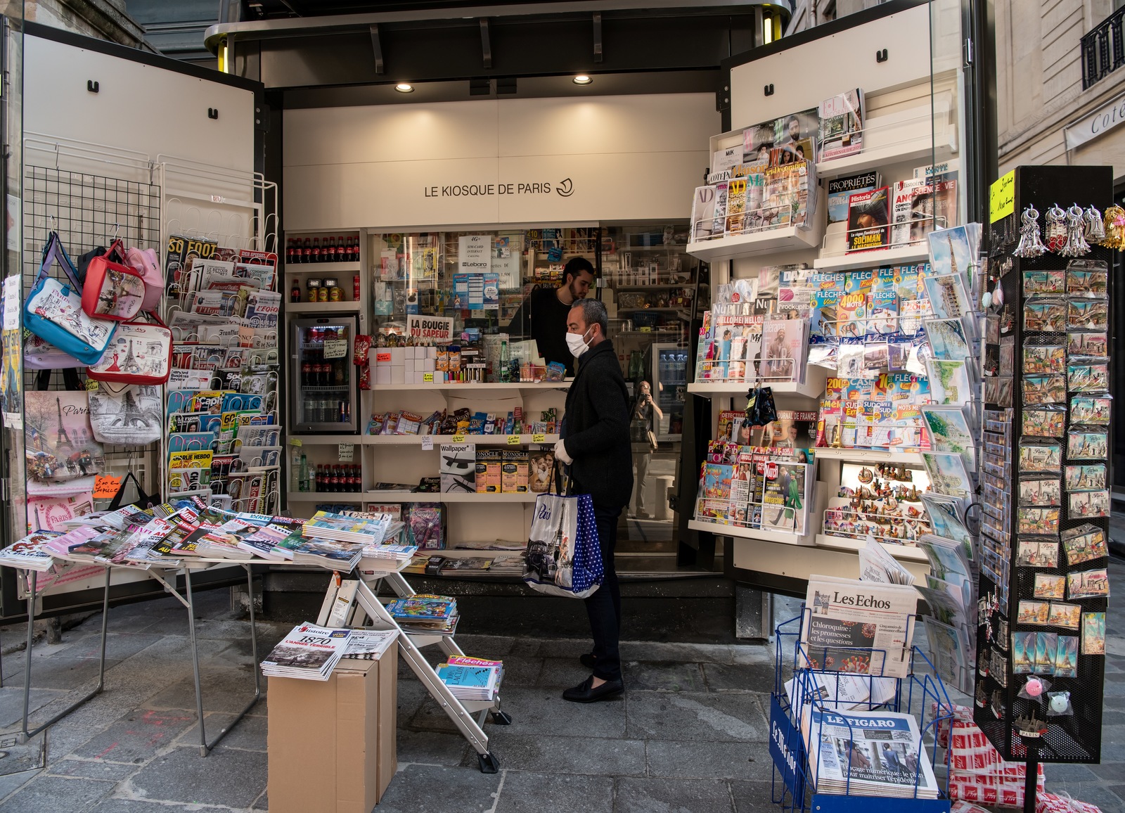 Un client achète un magazine dans un kiosque à Paris.