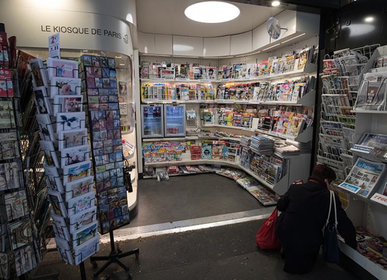 Une femme regarde une pile de journaux dans un kiosque de presse à Paris le 21 mars 2020 pendant le confinement suite à la pandémie de Covid-19.